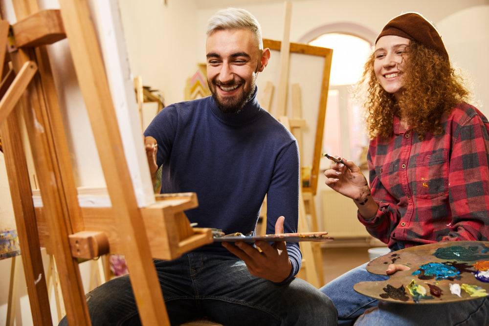 happy adults painting art on canvas