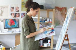 person standing and painting on canvas