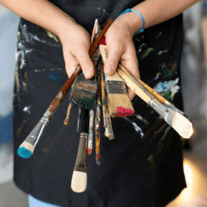 Teen holding painting tools, ready to create art.