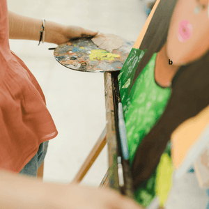 Teen holding a canvas with completed artwork on it.