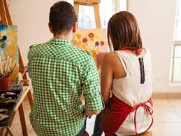 Couple drawing and painting on canvas, enjoying their creative time together.