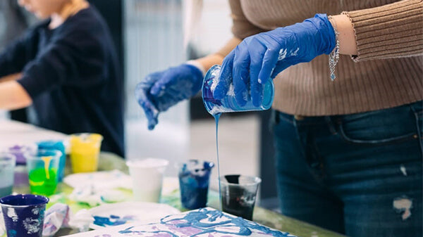 person pouring water color into a colorful board