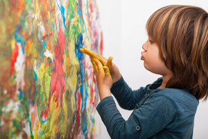 Kid painting with his hand, creating colorful artwork.