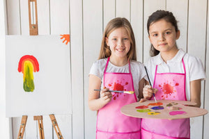 Two kids having fun together, painting and creating art with smiles on their faces.