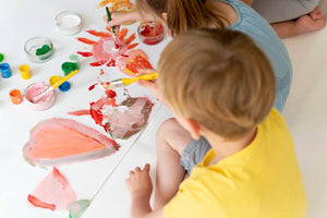 Kid sitting at a table, painting on a canvas with concentration